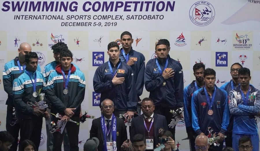 Maxwell de Silva officiating at the medal ceremony for the Mens 4x100m relay in swimming won by Sri Lanka.